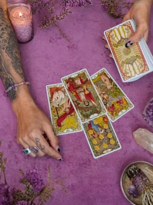 Consulta de tarot con cartas sobre mesa violeta, manos realizando lectura espiritual, cristales y ambiente místico.